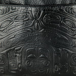 gros plan du motif autochtone traditionnel représentant un ours, estampé en relief sur un sac de cuir noir