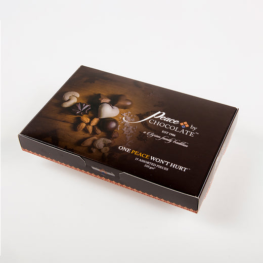 Une boîte de chocolats avec le texte « Peace by ChocolateTM, Est 1986, a Syrian family tradition, ONE PEACE WON’T HURTTM, 15 assorted pieces, 220 gm »