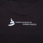 gros plan de l’image au dos de la chemise, soit le logo du Musée et le text « Canadian Museum for Human Rights »