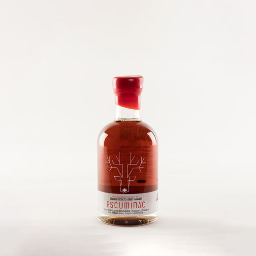 Bouteille de sirop d’érable scellée avec de la cire rouge; on voit l’illustration d’un orignal et le texte « Great Harvest, Escuminac, pure organic maple syrup, Canada Grade A / Grande récolte, Escuminac, sirop d’érable pur biologique, Canada catégorie A » sur la bouteille.