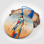 Décoration ronde décorée d’une œuvre d’art représentant une femme autochtone. La décoration est appuyée en angle sur un morceau de bois. 