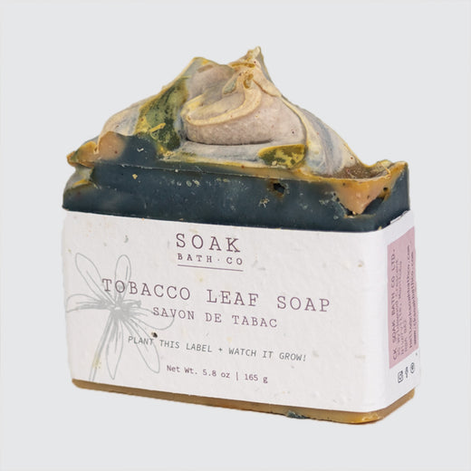 Savon de couleur saumon debout avec une étiquette simple qui dit : "Soak Soap Co." et "Savon de tabac".