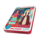 Contenant en métal montrant deux figures féminines historiques différentes, Frida Kahlo et Reine Élizabeth I. Sur le couvercle on peut lire « Magnetic Dress-Up » et « Girl Power! », en angle.